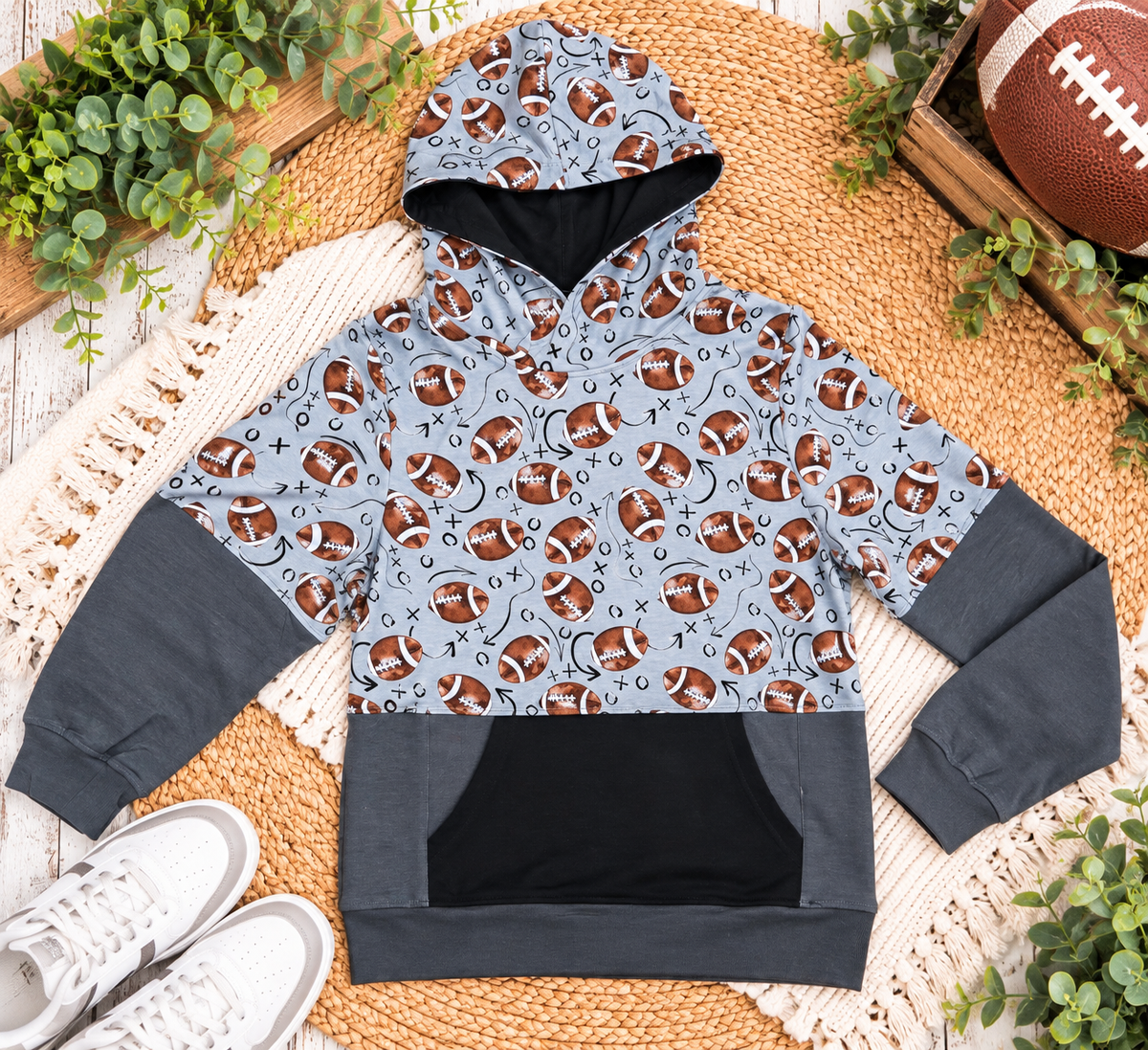 a grey and black hoodie with footballs on it