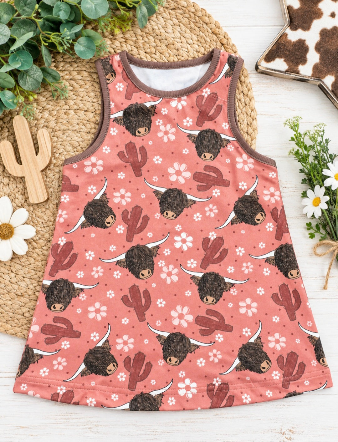a pink dress with bull faces and cactuses on a white surface